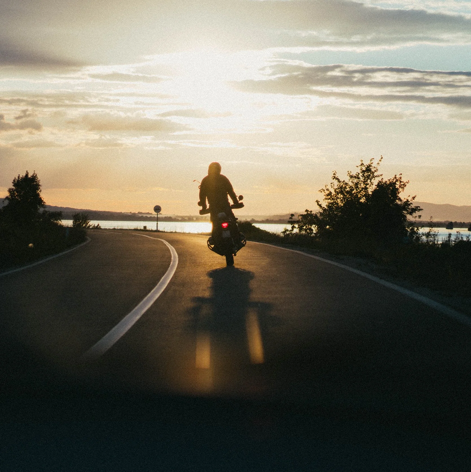 Motorcycle rider on an open road at sunset